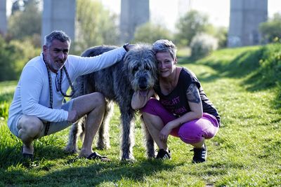 Portrait of senior couple with irish wolfhound on grassy field