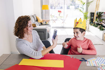 Mother and son making crafts at home with cardstocks and stickers