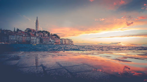 Scenic view of sea and buildings against sky during sunset