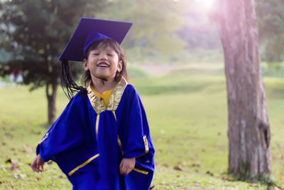Smiling girl wearing graduation gown while standing outdoors