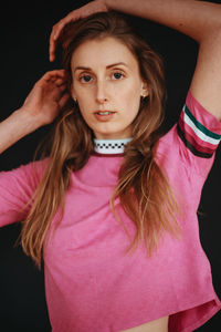 Portrait of beautiful young woman standing against black background