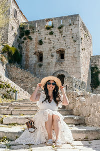 Front view of beautiful woman sitting on stone stairs in medieval fortress klis in split, croatia