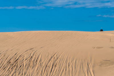 Sand dune in desert against blue sky