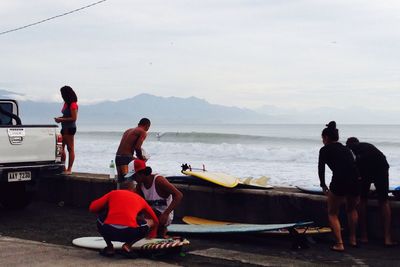 Men sitting on boat at beach against sky