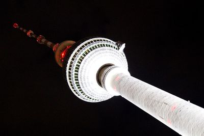 Low angle view of illuminated lighting equipment against black background