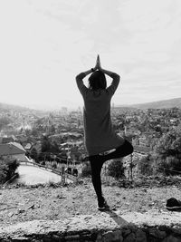 Rear view of woman in tree pose against cityscape