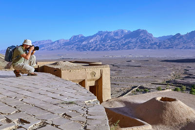 Man wearing hat against mountains against blue sky