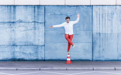 Full length of young man standing against wall