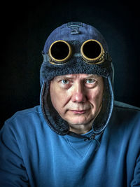 Portrait of man wearing mask against black background