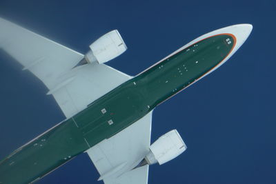 Low angle view of airplane flying against clear blue sky