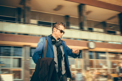 Businessman checking the time while standing in city