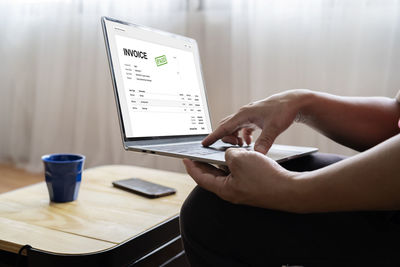 Midsection of man using mobile phone on table