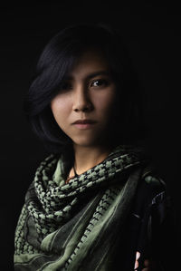 Portrait of young woman against black background