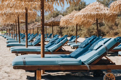 Side view of a row of empty blue sun beds under parasols on a beach in mykonos, greece.