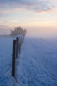 Scenic view of snow covered field against sky during sunset