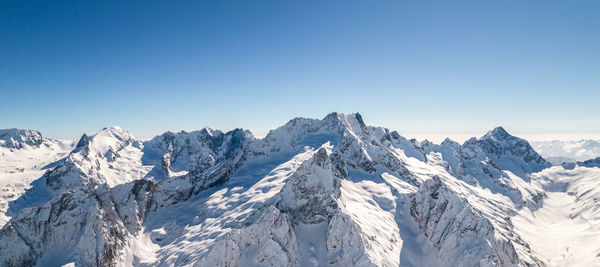 Scenic view of snowcapped mountains against clear blue sky