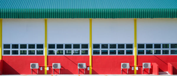 Air conditioner compressor installation on red building wall, outdoors