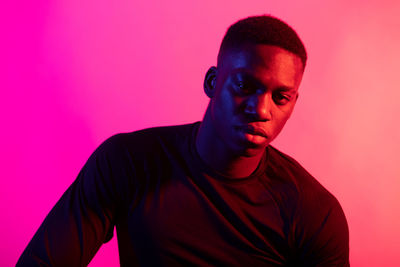 Portrait of young man against pink background