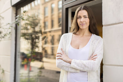 Portrait of owner with arms crossed standing outside clothing store