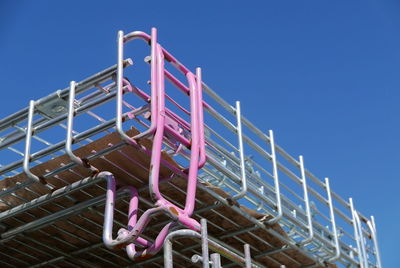 Low angle view of emergency ladder against clear blue sky