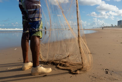 Fisherman is seen manipulating fishing net on the beach of jaguaribe