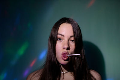 Portrait of beautiful young woman licking lollipop