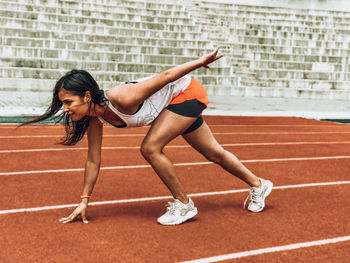 Side view of woman exercising on sports track