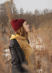 Side view of young woman standing in park during winter