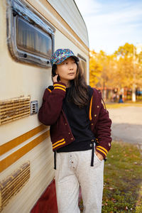 Portrait of young woman standing against building