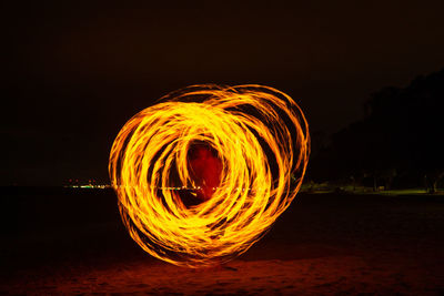 Light trails on beach against sky at night