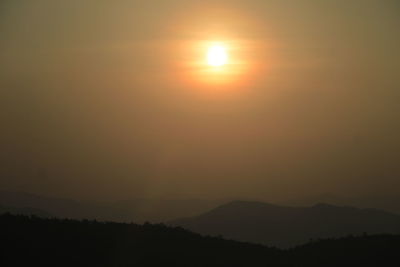 Scenic view of silhouette mountains against orange sky