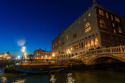 View of illuminated buildings by canal at night