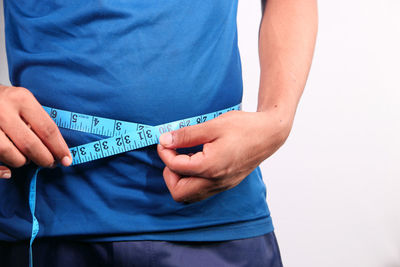 Midsection of man holding paper while standing against white background