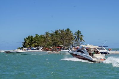 Boats sailing in sea against clear blue sky