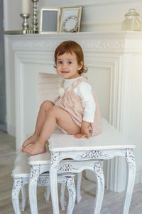 Portrait of cute girl sitting on sofa at home