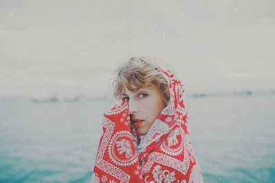 Portrait of beautiful woman wearing scarf against sea at beach