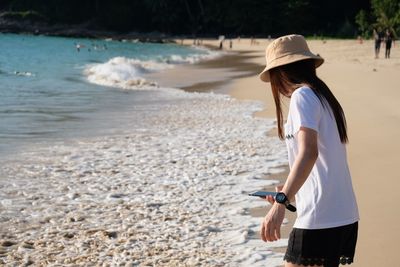 Side view of woman using mobile phone standing on beach