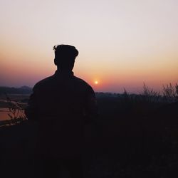 Rear view of silhouette man standing against sky during sunset