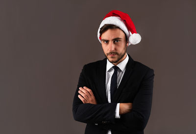 Portrait of young man standing against black background