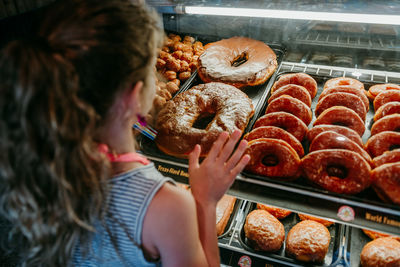 Rear view of girl looking at donuts in store