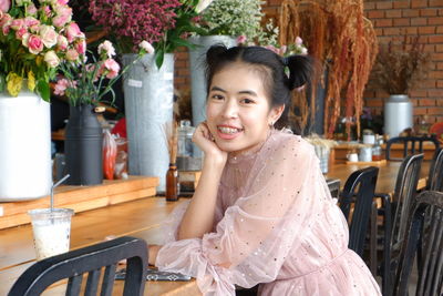 Portrait of a smiling young woman sitting on table