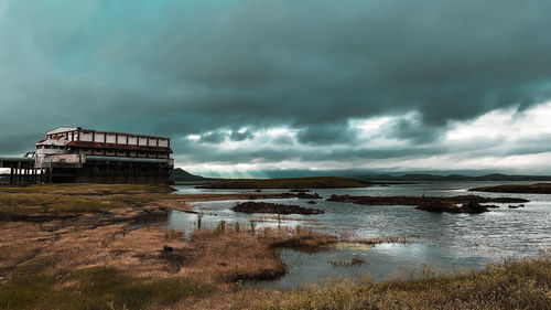 Built structure by sea against storm clouds