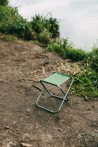 An empty chair for relaxing or fishing stands on the bank of a river or lake