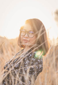 Portrait of smiling woman on field against sky