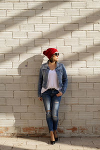 Attractive blond woman posing against wall while looking away