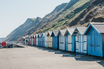 Unidentifiable people in the distance, walking by colourful beach huts in sheringham, norfolk, uk.