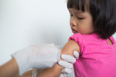 Cropped hands of doctor injecting girl at hospital
