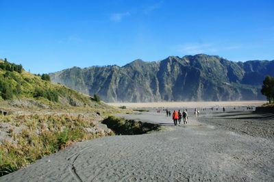 People walking on road along landscape