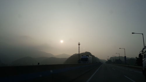 Cars on road against sky during sunset
