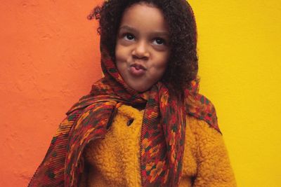 Close-up of girl puckering lips while standing against colorful wall